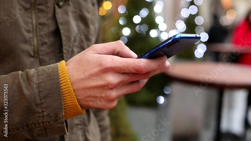 Closeup of man hand using smartphone outside. Winter traveling. Online communication with friends. Typing chat message. Internet searching. Freelance lifestyle. Tapping touchscreen phone.