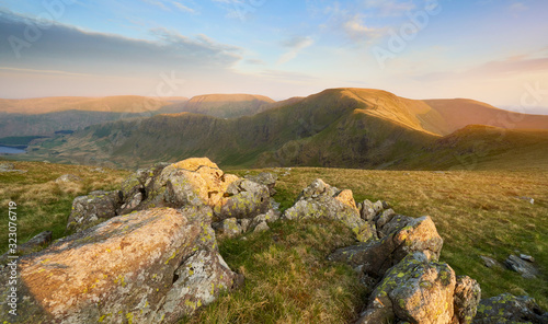 The warm evening glow as sunset approaches over the summit of High Street with Mardale Ill Bell and Harter Fell to the left and Thronthwaite to the right. Rampsgill Head in the Lake District. photo