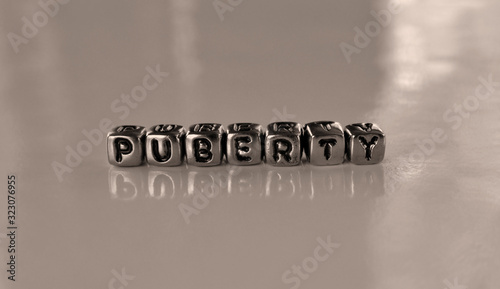 Puberty -  word from metal blocks - concept sepia tone photo on shine background