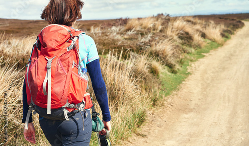 Photo A closeup view of a female hiker walking along a trail on the moors with a red backpack on a sunny autumn day in Blanchland, County Durham