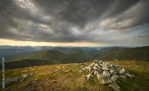 Dark clouds gather over the mountains in the evening just before sunset from the summit of Rampsgill Head with Rest Dodd, The Nab and Martindale Common in the in the Lake District. © Duncan Andison