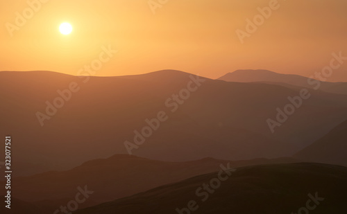 Late evening glow of sunset over the mountains of the Lake District UK from the summit of Rampsgill Head with The Knott just below.