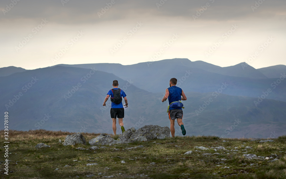 CUMBRIA, ENGLAND, UK - MAY 18, 2018: Two fell runners running along a mountain trail.