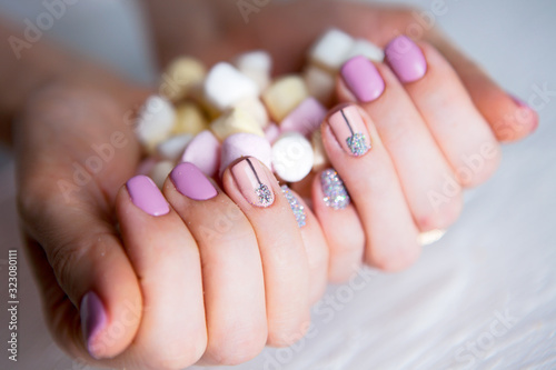 pink glitter nails with marshmallow candies on woman's hand. colourful vivid manicure on lady fingers