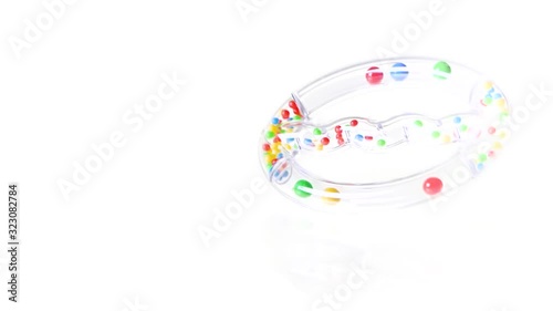 Transparent baby rattle toy spinning on white background in 8x slow motion photo