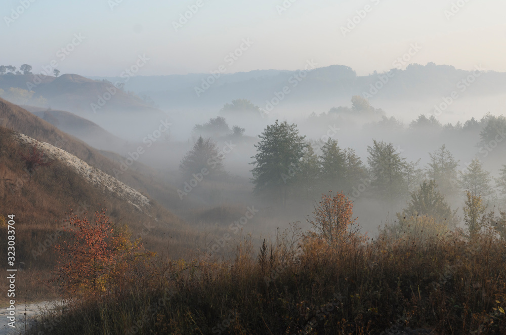 Dawn on a foggy morning, trees and hills in the fog, beautiful morning light and magical atmosphere. Dawn on a foggy morning, trees and hills in the fog, beautiful morning light and magical atmosphere.