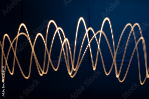 Segni luminosi a forma di onda sinusoidale ottenuti muovendo una torcia elettrica nel buio photo