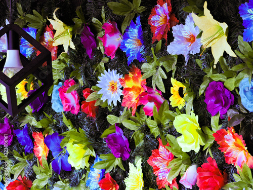 mural de flores de colores y hojas iluminadas por una lampara colgante 