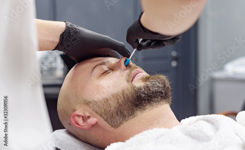 beard modeling in Barber shop, removing hair from the nose and ears with wax, male beauty and care concept