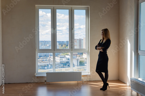 Slender girl stands at a large stained glass window in an empty room