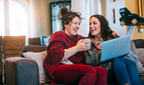 Two female friends watching something funny on a tablet at home