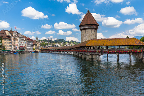 Beautiful view of Chapel Bridge (Kapellbruecke) and Water Tower (Wasserturm) with Lucerne old town in background and Reuss river flowing to lake, on sunny summer day with blue sky cloud, Switzerland © Peter Stein