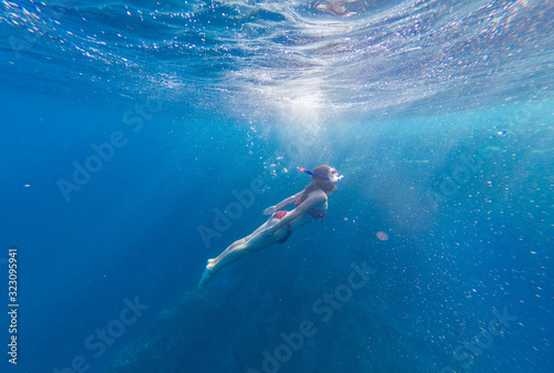 Girl with a mask and a snorkel dives into the sea with corals and fish © Дмитрий Ткачук