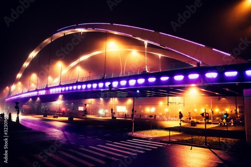 Illuminated bridge and a city street on a foggy night