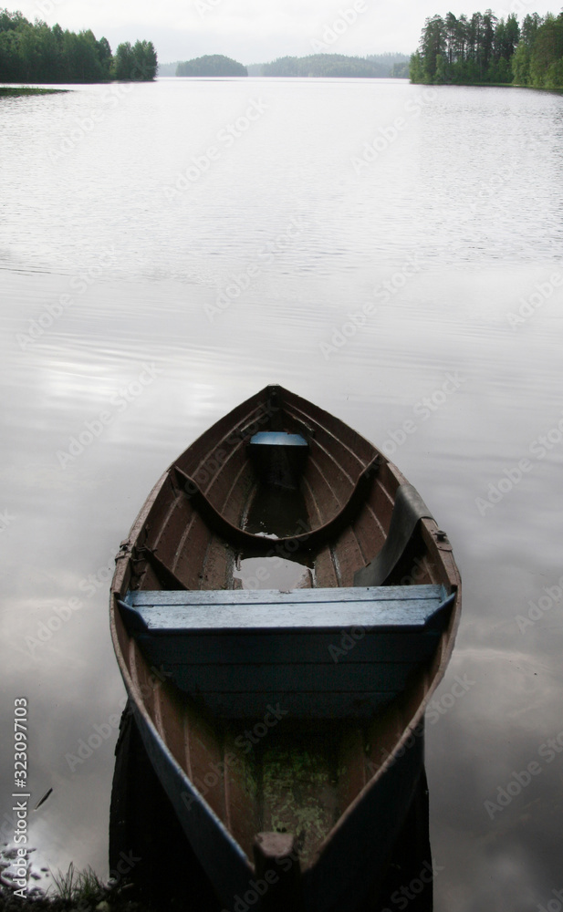 An old, lonely boat on the shore of a pond.