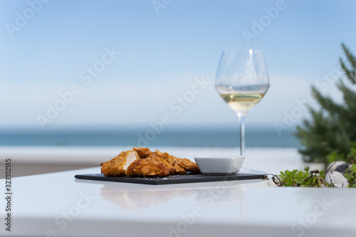 Foto Fried chicken served with sauce in a dark board with a glass of wine in a table