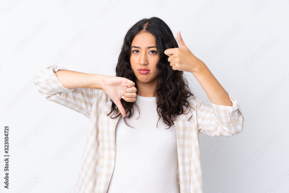 Mixed race woman over isolated white background making good-bad sign. Undecided between yes or not Mixed race woman over isolated white background making good-bad sign. Undecided between yes or not