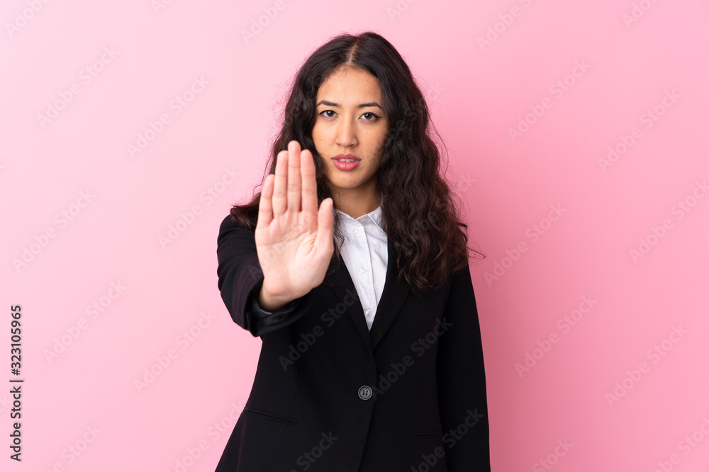 Mixed race business woman over isolated pink background making stop gesture with her hand Mixed race business woman over isolated pink background making stop gesture with her hand