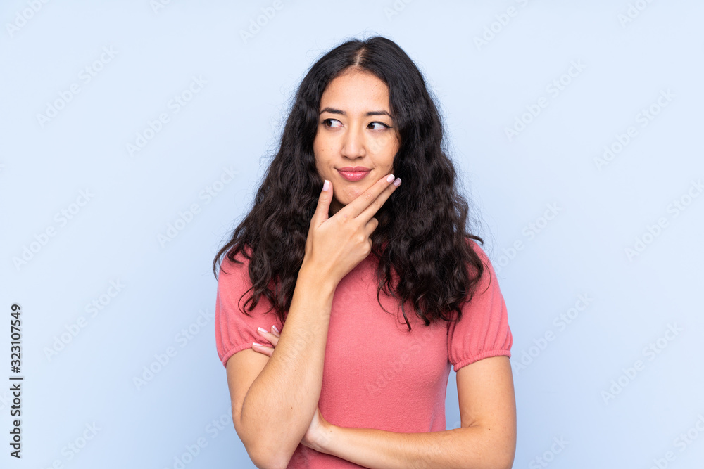 Mixed race woman wearing a sweater over isolated blue background thinking an idea Mixed race woman wearing a sweater over isolated blue background thinking an idea