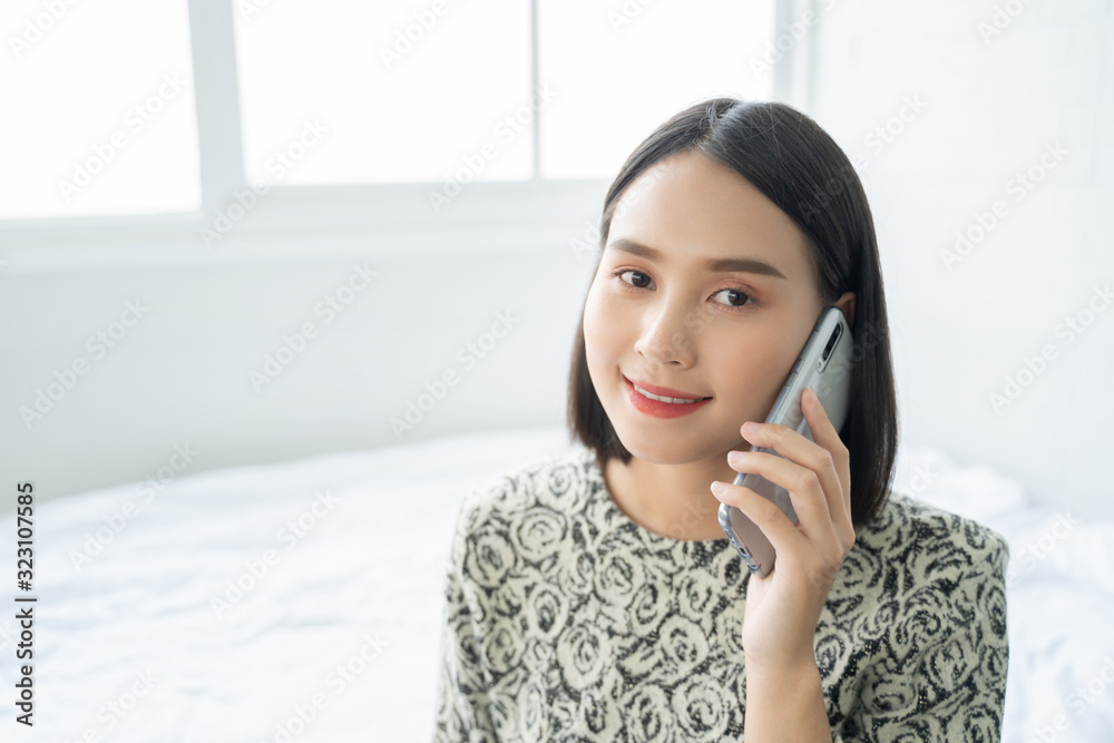 Asian woman talk by mobile phone calling texting on the bed ,in bed room Asian woman talk by mobile phone calling texting on the bed ,in bed room