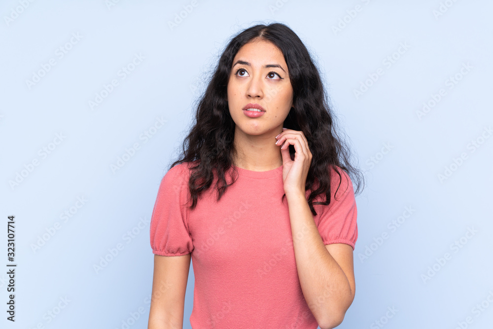 Mixed race woman wearing a sweater over isolated blue background thinking an idea Mixed race woman wearing a sweater over isolated blue background thinking an idea