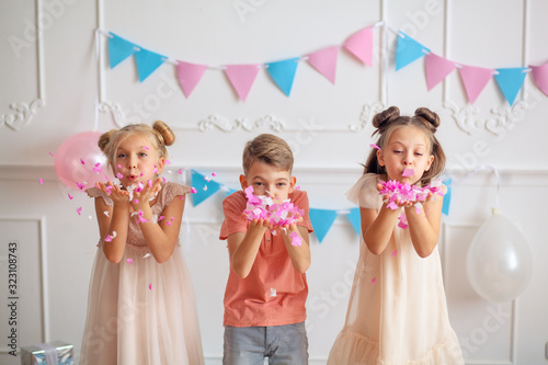 Happy birthday Happy cute children in festive decor and beautiful dresses play with confetti.