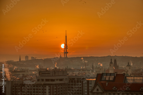 prague tv tower at sunrise wirh roofs and birds flying
