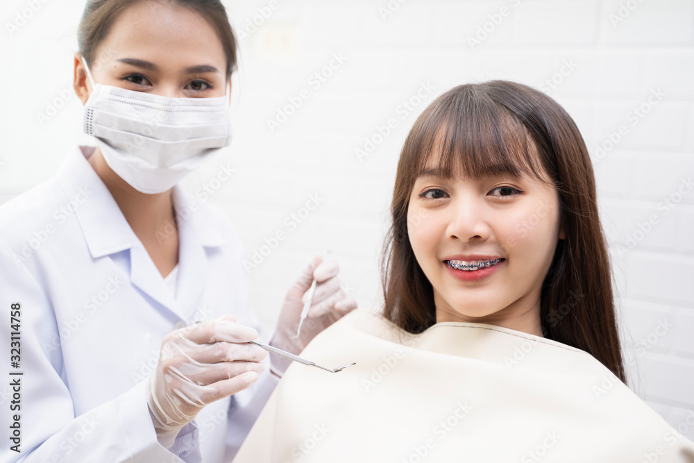 Asian Doctor Dentist examine female patient with braces in a dental office, wearing gloves standing in clinic check Close Up young braces Asian woman, Beautiful Asian girl smiles in dentistry.