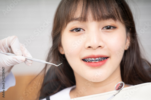 Asian Doctor Dentist examine female patient with braces in a dental office  wearing gloves standing in clinic check Close Up young braces Asian woman  Beautiful Asian girl smiles in dentistry.
