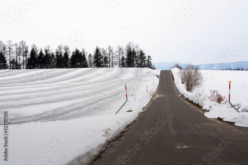 融雪剤がまかれた雪の畑と道路