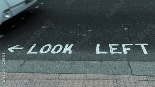 Schriftzug auf einer Straße LOOK LEFT mit einer Busfront von links photo