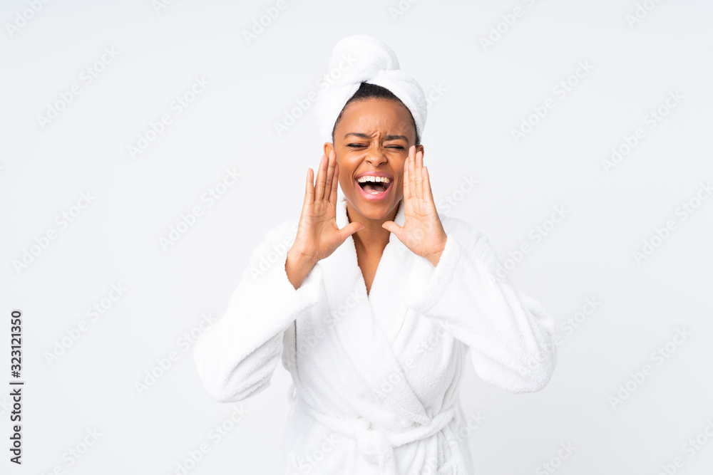 African american woman in a bathrobe over isolated background shouting with mouth wide open African american woman in a bathrobe over isolated background shouting with mouth wide open
