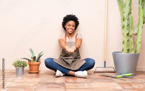 Gardener woman sitting on the floor holding copyspace imaginary on the palm to insert an ad