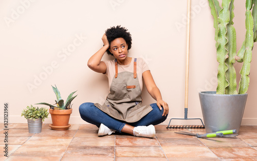 Gardener woman sitting on the floor with an expression of frustration and not understanding