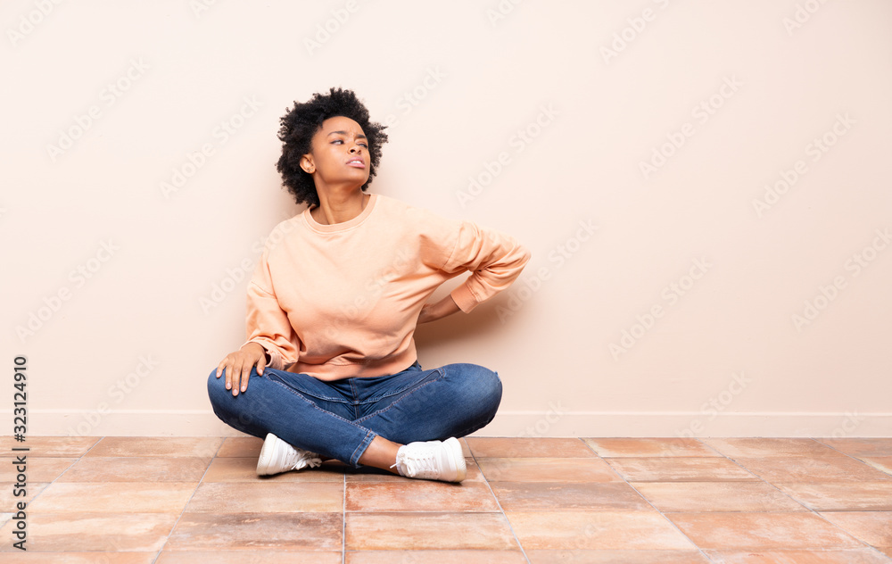 African american woman sitting on the floor suffering from backache for having made an effort