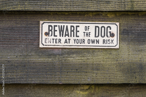 A little white and black BEWARE OF THE DOG sign on an old seamless green wooden background.