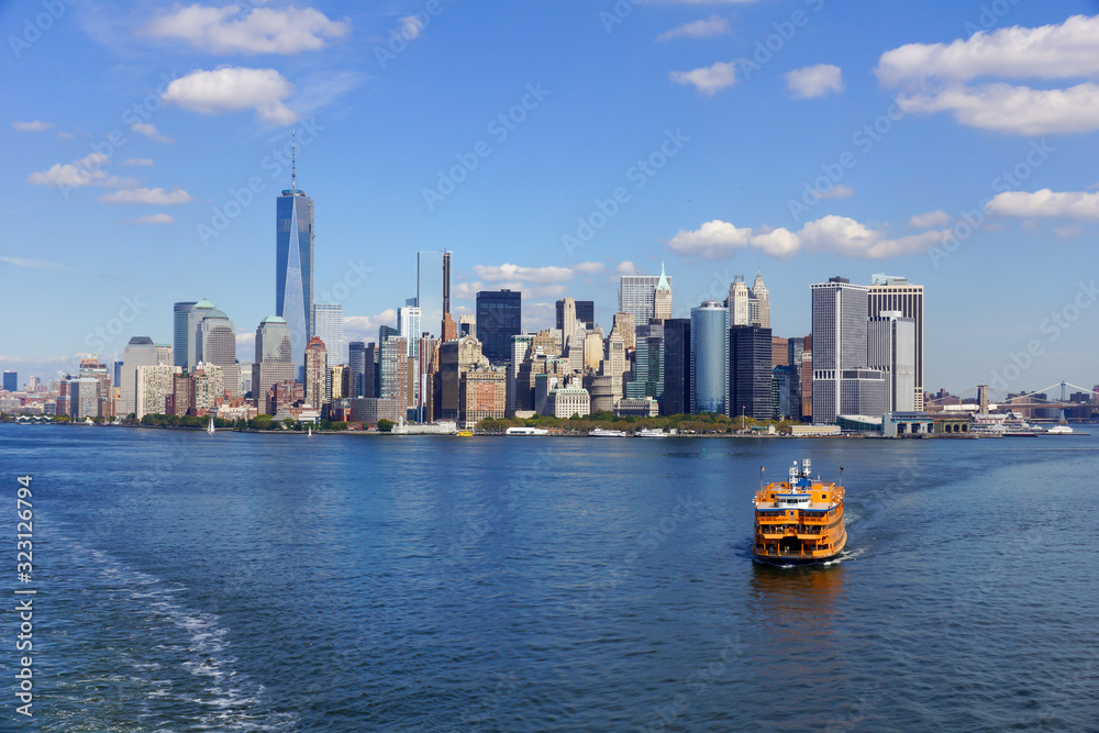 Fototapeta premium view across the water to the skyline of new york, yellow boat in front
