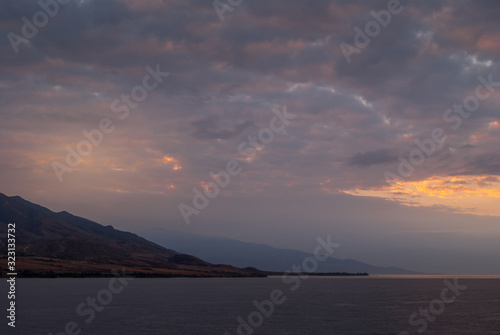 Lahaina, Maui, Hawaii, USA. - January 12 2012: Early morning light over ocean while approacing West side on dark ocean under spectacular cloudscape as if heaven is on fire. Shape of coastline hills. © Klodien