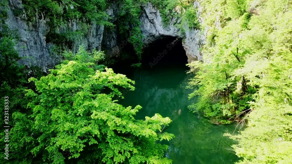 Aerial view of Cerknica Cave, Slovenia, with a river flowing in, surrounded by a forest Aerial view of Cerknica Cave, Slovenia, with a river flowing in, surrounded by a forest