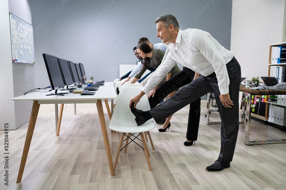 Businesspeople Doing Stretching Exercise At Workplace