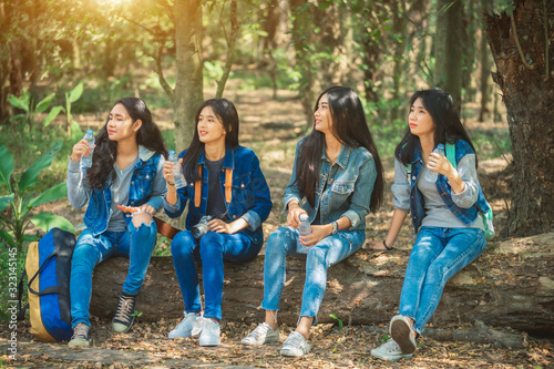 Asian group girls, they stop drinking water and relaxing during hiking.