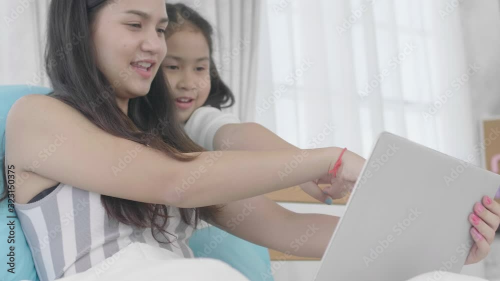 Asian girls and sisters are using laptops, computers and tablets to connect to the cyber world. The little girl rested at home using the internet. Asian girls and sisters are using laptops, computers and tablets to connect to the cyber world. The little girl rested at home using the internet.