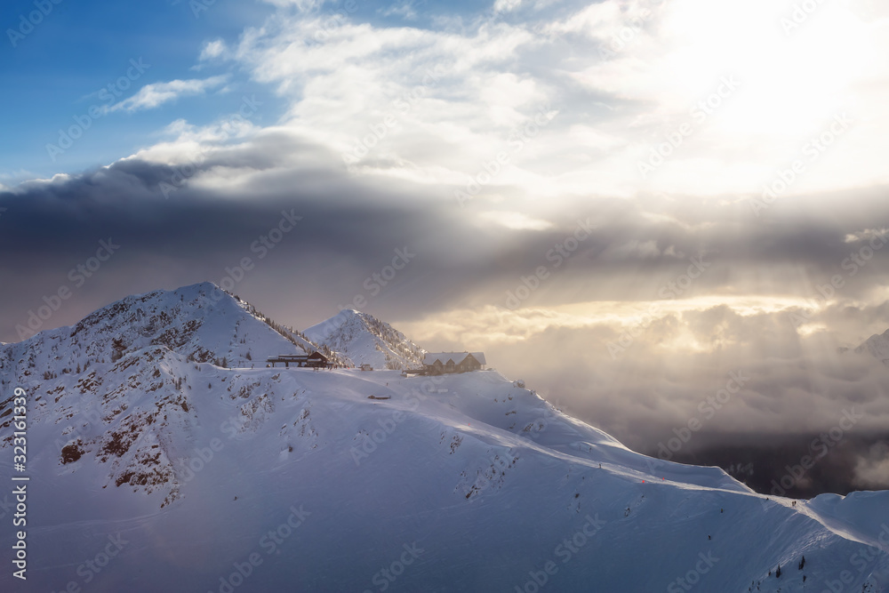 Obraz premium Kicking Horse, Golden, British Columbia, Canada. Beautiful Aerial View of Canadian Mountain Landscape during a vibrant sunny and cloudy morning sunrise in winter. Chalet and Gondola