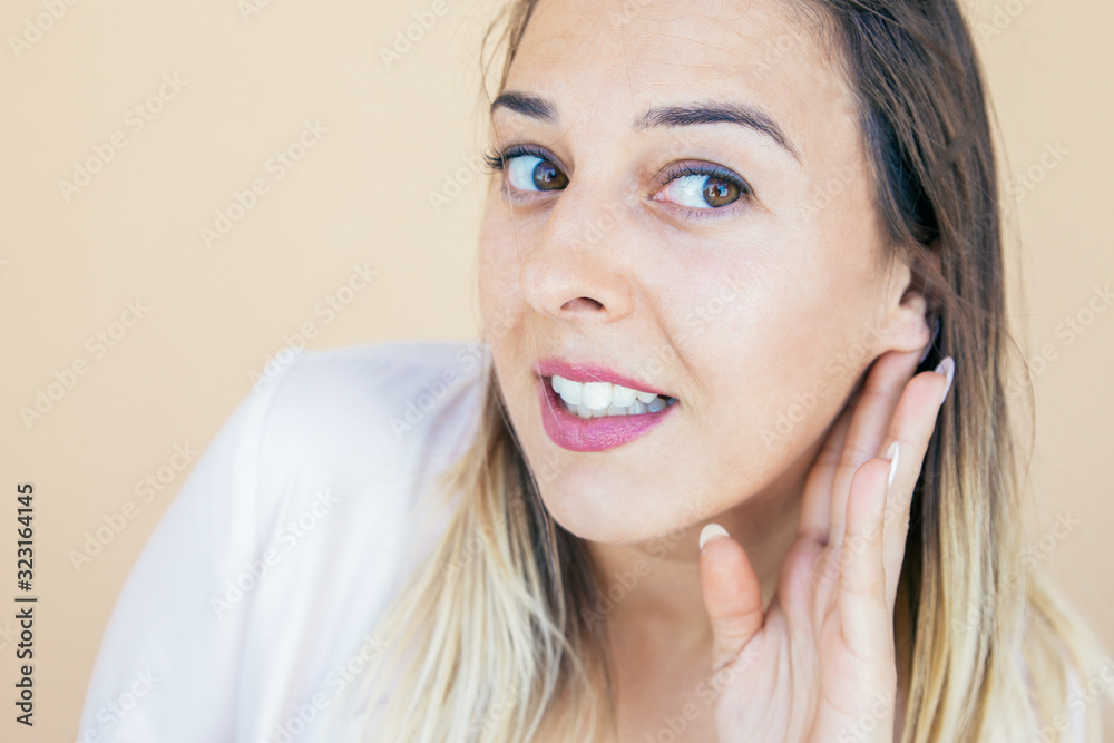 Excited curious lady hearing secret news or gossips. Young woman in casual keeping hand at ear and listening carefully. Curiosity concept Excited curious lady hearing secret news or gossips. Young woman in casual keeping hand at ear and listening carefully. Curiosity concept