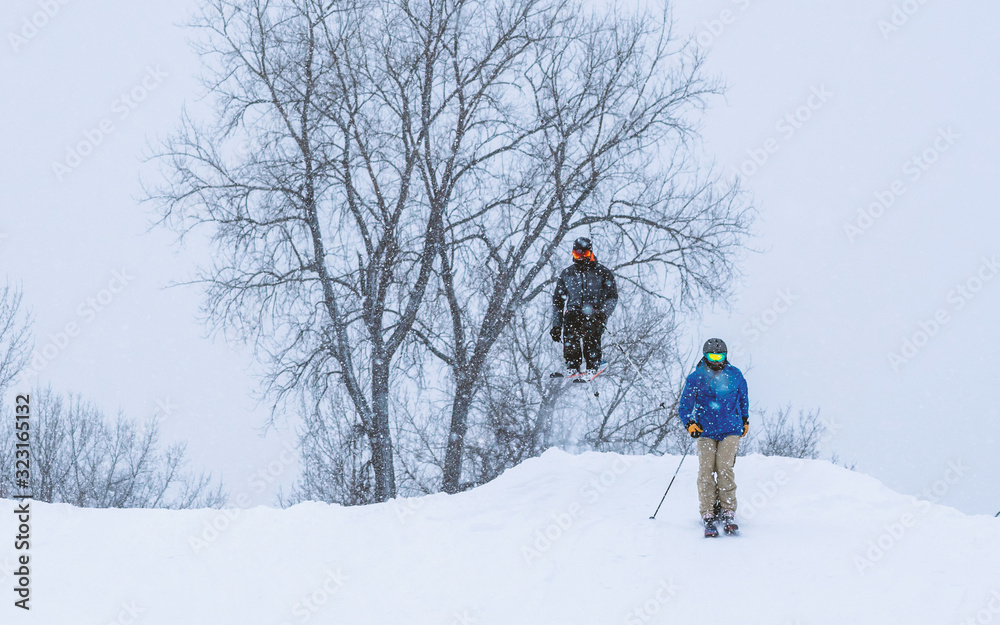 People are having fun in downhill skiing and snowboarding in the middle of snowfall