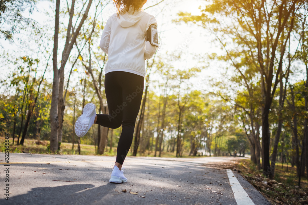 Fototapeta premium Rear view image of a young asian woman jogging in city park in the morning