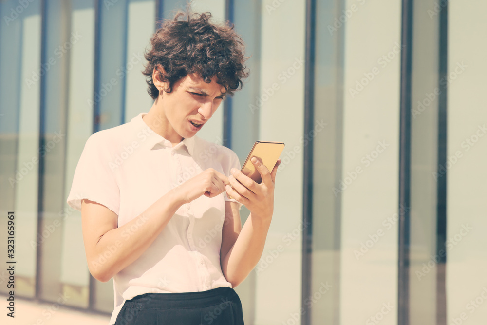Serious woman using smartphone outdoor. Middle aged businesswoman messaging via mobile phone outside modern building. Technology concept Serious woman using smartphone outdoor. Middle aged businesswoman messaging via mobile phone outside modern building. Technology concept