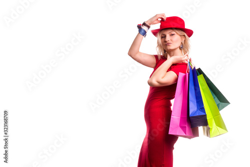 blonde girl with short hair on isolat in a red dress and a red hat, with colored paper shopping bags. The concept of shopping or sales,