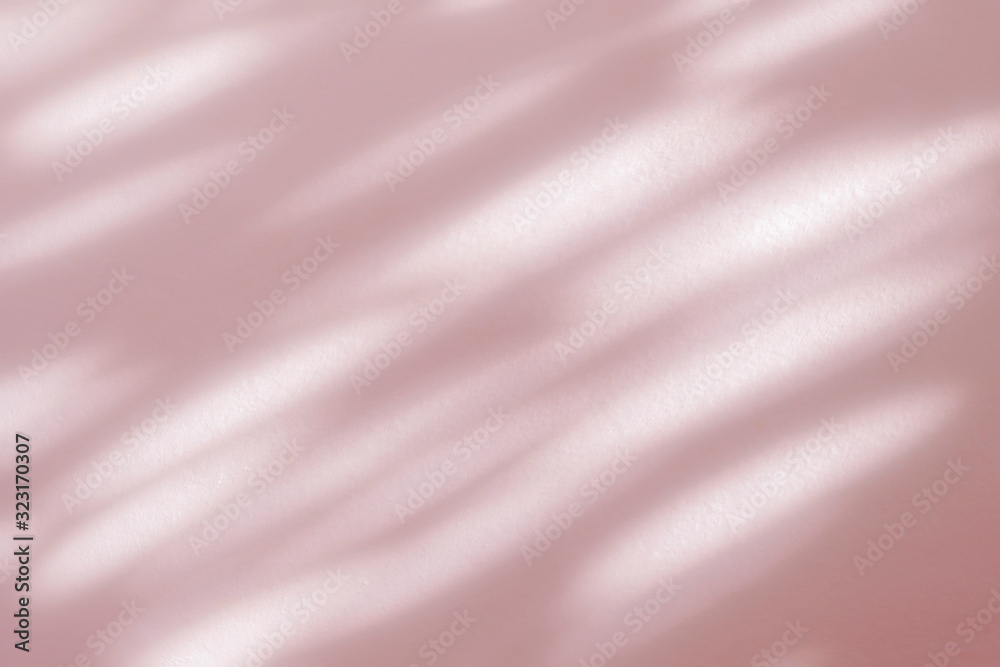 Fototapeta premium Abstract leaves shadow blurred background. Natural leaves tree branch foliage pink rose gold diagonally shadows and sunlight on white wall