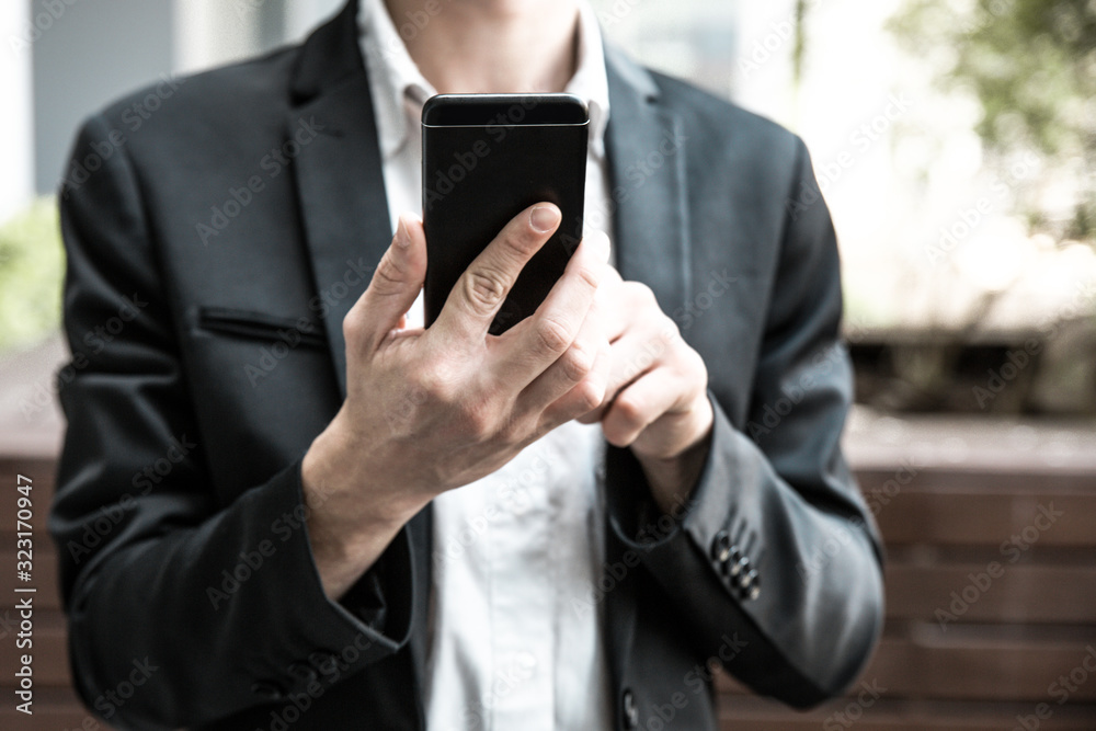 Businessman using app or taking picture on smartphone outside. Man in office holding cellphone. Communication or wireless technology concept Businessman using app or taking picture on smartphone outside. Man in office holding cellphone. Communication or wireless technology concept